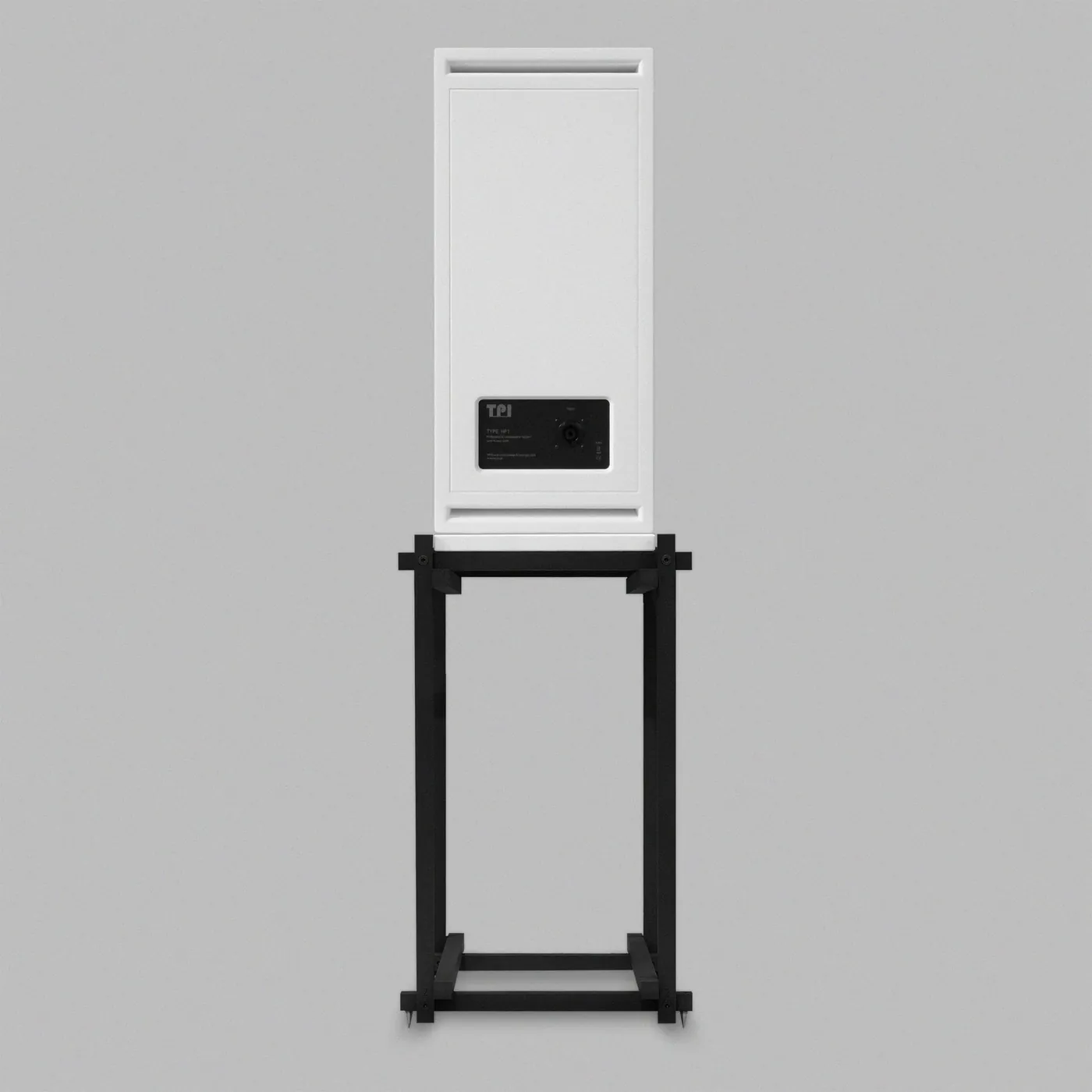 Rear of the Type. HF1 on its stand: a plain white back with a slot at the top and a black connection plate, on the open black square-bar stand.