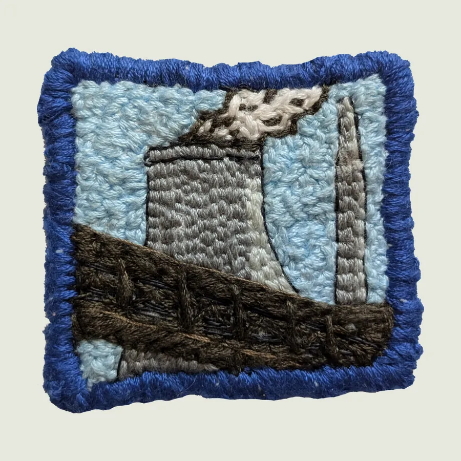 Square embroidered patch edged in blue: a grey cooling tower and chimney with white steam, crossed by a brown steel truss bridge, against a light blue sky.
